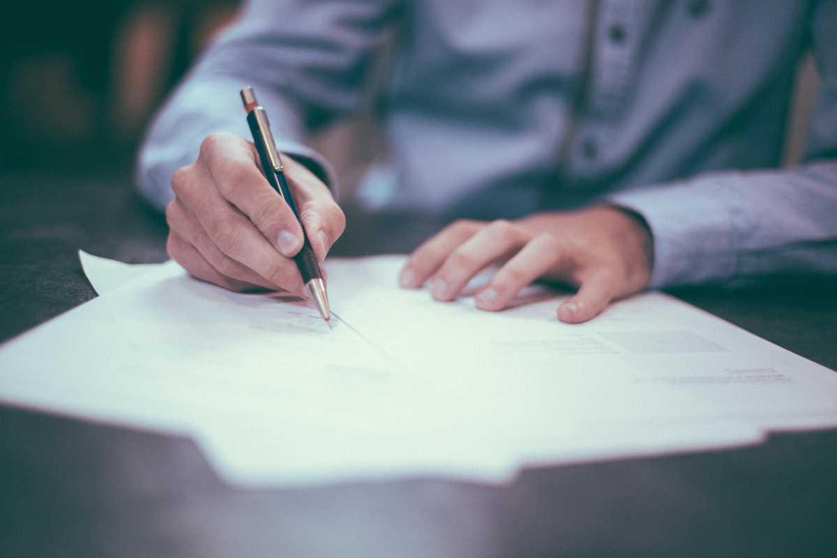 Person signing document - Credit to @homajob, image supplied via Unsplash