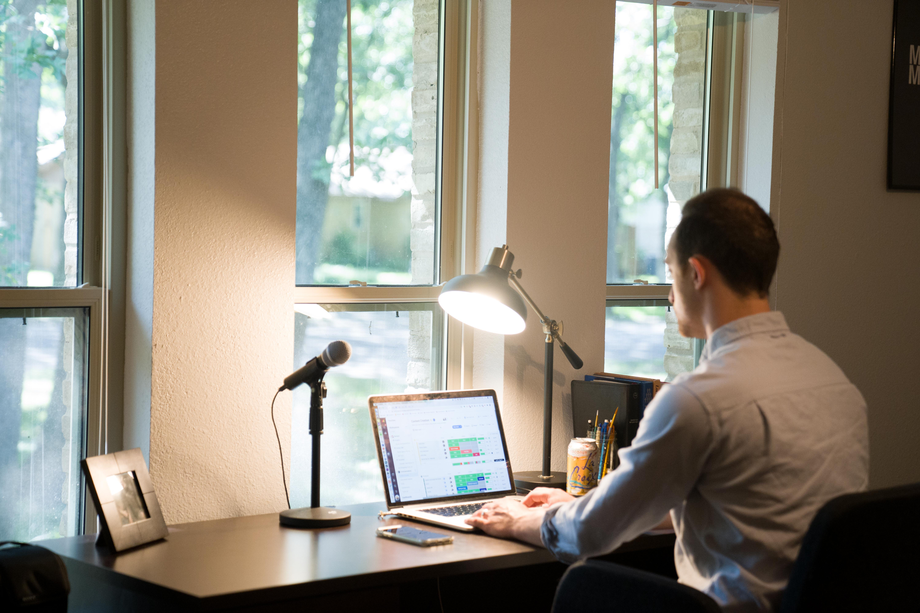 man sitting at desk working using laptop in home office - Credit to @ianharber, image supplied via Unsplash