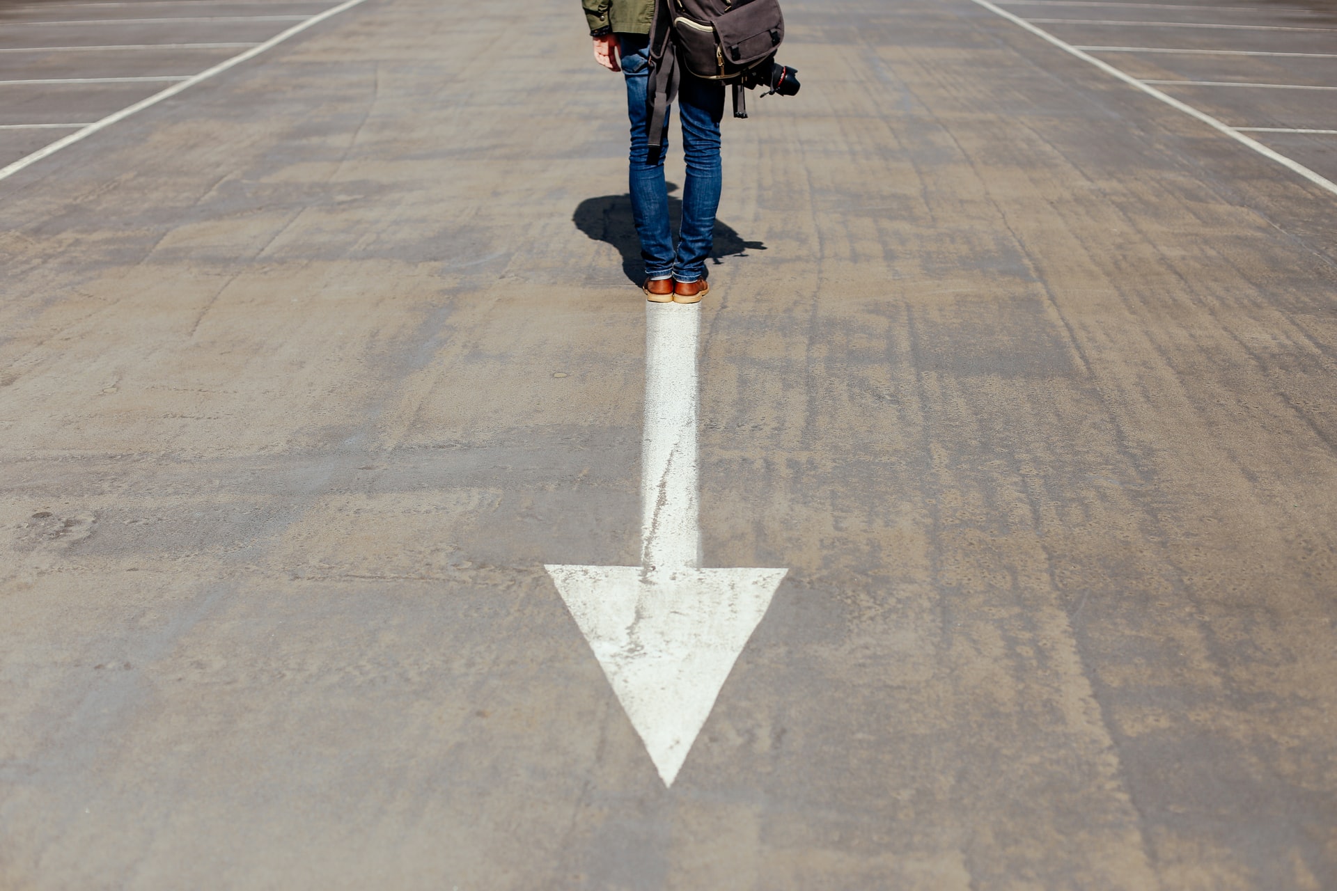 Man standing on arrow. Photo by @smartphotocourses via Unsplash