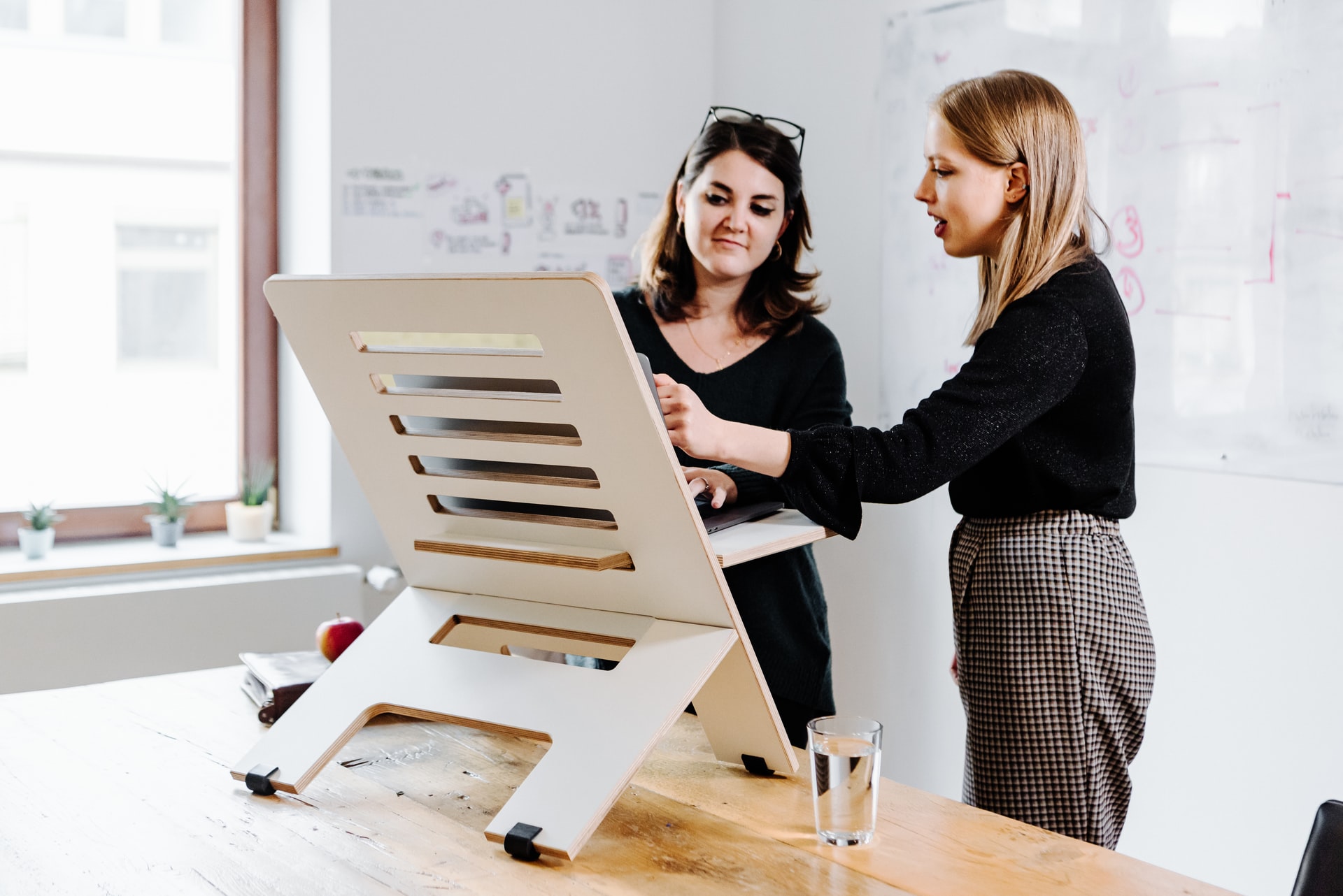 Two colleagues working at a standing desk. Photo by @standsome via Unsplash.